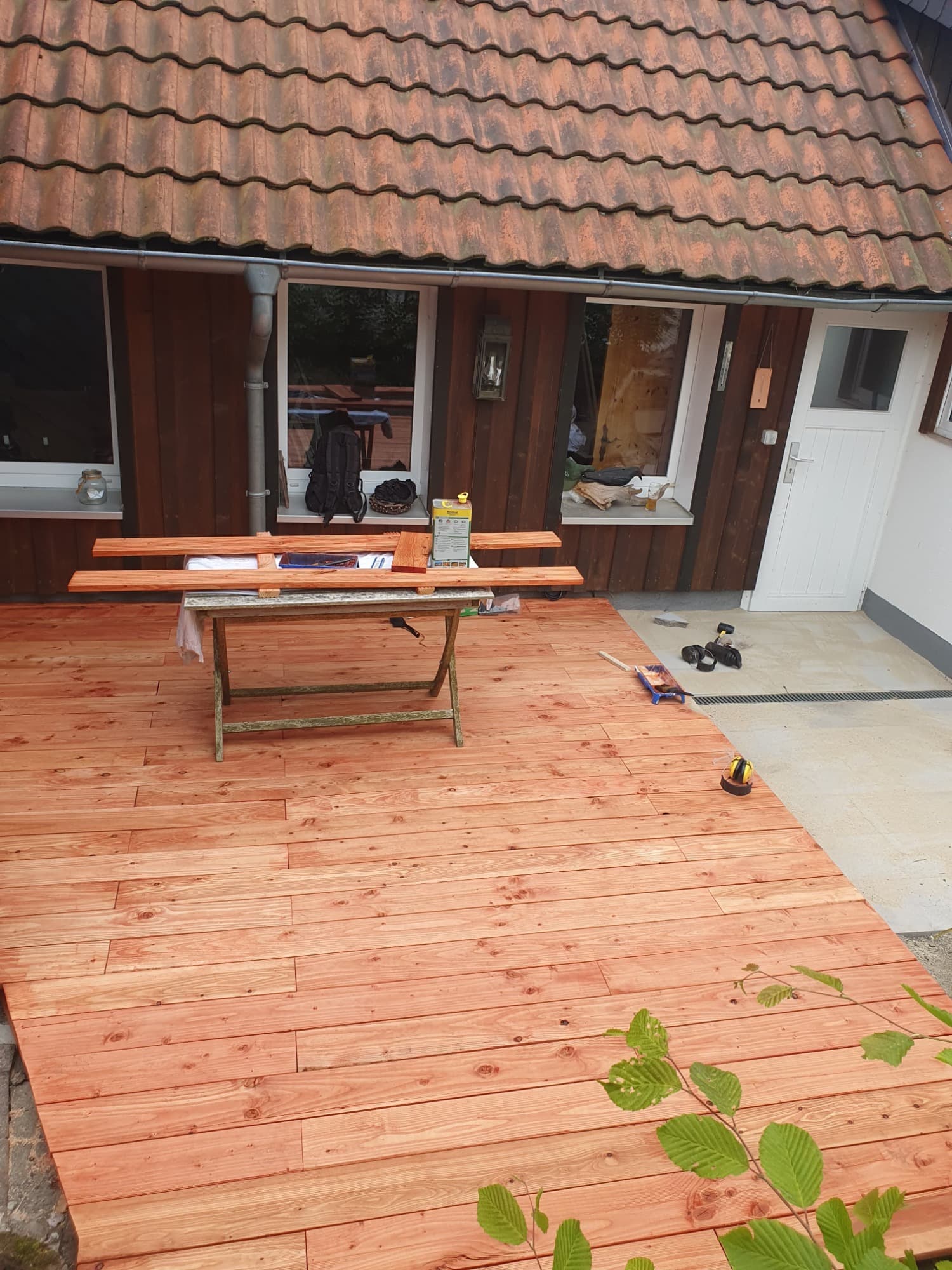 Frisch verlegte, hell geölte Holzterrasse vor einem Harzer Ferienhaus, auf einem Bock liegen zugeschnittene Dielen.